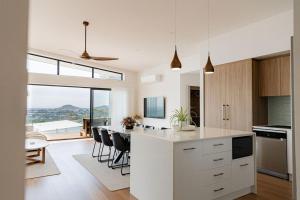 a kitchen with white cabinets and a table with chairs at Surfscape in Bicheno