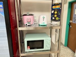a microwave and other appliances on a shelf at Hippo House Taiping in Taiping