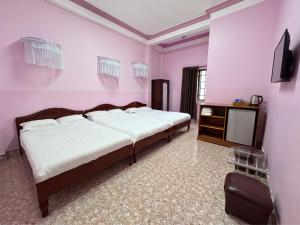 a pink bedroom with two beds and a television at Nhat Quynh Hotel in Da Lat