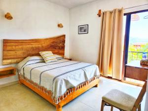 a bedroom with a bed with a wooden headboard and a window at Casa Flores in Tepoztlán