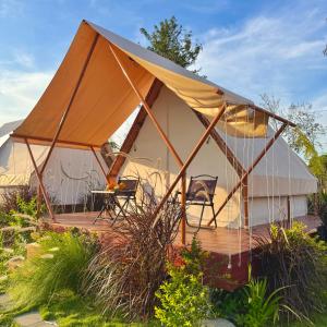 The Lake Farm - Dak Lak في بون ما توت: خيمة مع كراسي وطاولة في حديقة