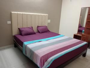 a bedroom with a large bed with purple pillows at hope villa homestay gokarna in Gokarna +24 photos