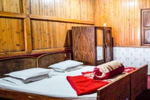 a bed in a wooden room with a red blanket on it at Rongo White House by StayApart in Kumai