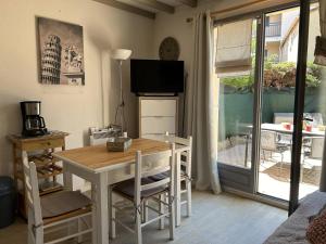 a dining room with a table and chairs and a television at Mazet climatisé 3 pièces avec piscine et parking, quartier calme, Le Lavandou - FR-1-251-840 in Le Lavandou