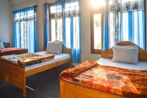 two beds in a room with blue curtains at Abhinay Natural Homestay by StayApart in Gorubathān