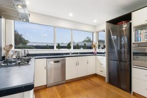 a kitchen with white cabinets and a stainless steel refrigerator at Christchurch Home away from home in Christchurch