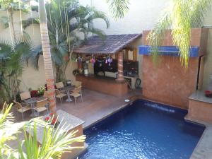 a swimming pool next to a building with a house at Hotel Mercurio - Gay Friendly in Puerto Vallarta