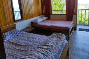 two beds in a room with two windows at Nature Love Homestay By StayApart in Takdāh +5 photos