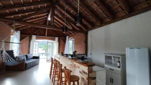a kitchen with a counter with chairs and a refrigerator at casa de campo Chalé bela vista in Tijucas