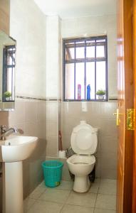 a bathroom with a toilet and a sink and a window at Honey Suite Two Bedroom Master & Suite Apartments in Nairobi