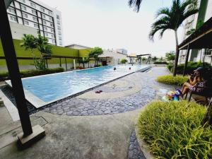 a swimming pool with people sitting next to a building at Steff's Condo 1708 one bedroom at Centrio Tower in Cagayan de Oro