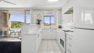una cucina con mobili bianchi e vista sull'oceano di Ocean Parade 9 - Cafes, Stroll to beach, BBQ, Pool a Coffs Harbour