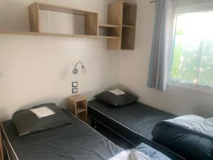 two twin beds in a room with a window at Mobilhomme camping in Fréjus