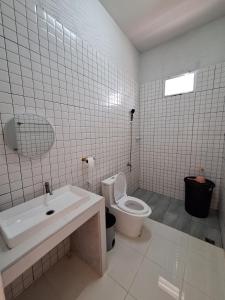 a white bathroom with a toilet and a sink at Phu Aunna in Ko Phayam