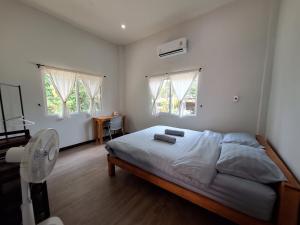 a bedroom with a bed and a fan and windows at Phu Aunna in Ko Phayam