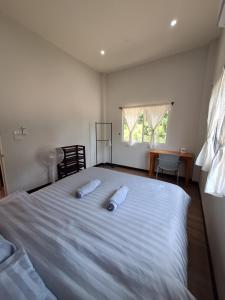 a bedroom with a large white bed with two pillows on it at Phu Aunna in Ko Phayam