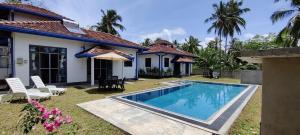 a villa with a swimming pool in front of a house at Villa Nil Akurala in Kahawa
