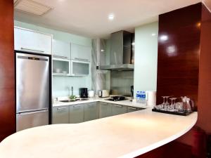 a kitchen with white cabinets and a stainless steel refrigerator at Tianjin Crown International Apartment in Tianjin