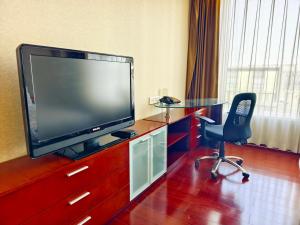 a room with a tv and a chair and a table at Tianjin Crown International Apartment in Tianjin