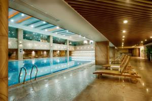 a swimming pool in a building with lounge chairs at KB Hotel Qingyuan in Qingyuan