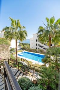 a swimming pool with palm trees and a building at Sea view apartments with Year-Round Open Pool in Manilva