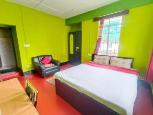 a bedroom with green walls and a bed and a chair at Pumpkin Lapalang Stay House in Shillong