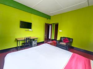 a bedroom with a bed and a desk and a tv at Pumpkin Lapalang Stay House in Shillong