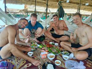 a group of men sitting around a table eating food at Dolphin Home Stay New in Kratie