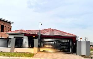 a building with two garage doors and a red roof at Zaidi Luxury Home in Secunda