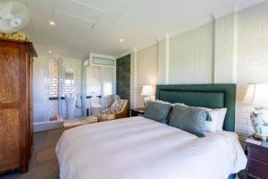 una camera da letto con un grande letto bianco con testiera verde di Glen Ormond Country House a Henburg Park