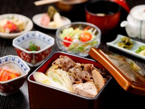 a table topped with bowls of food and vegetables at Kanazawa Hakuchoro Hotel Sanraku -Natural Hot Spring- in Kanazawa