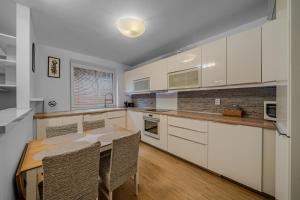 a kitchen with white cabinets and a wooden table at HUGE APARTMENT next to train station close to the city center in Staré Mesto