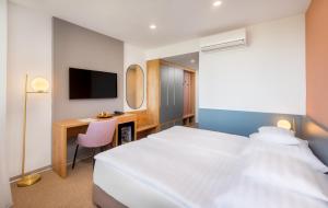 a bedroom with a bed and a desk and a tv at Hunguest Hotel Béke in Hajdúszoboszló