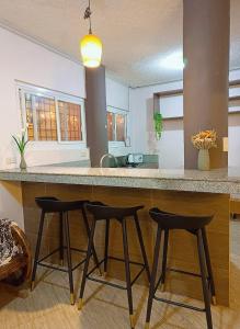 a kitchen with three bar stools at a counter at Spacious modern home near town in Baguio