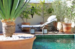 - un lit installé à côté d'une piscine entourée de plantes dans l'établissement Dar Mo'Da, à Marrakech