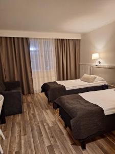 una habitación de hotel con dos camas y una silla en Juthbacka Hotell, en Uusikaarlepyy