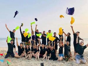 a group of people on the beach with their hands in the air at Vườn Dừa Cam Bình 1 in Lagi