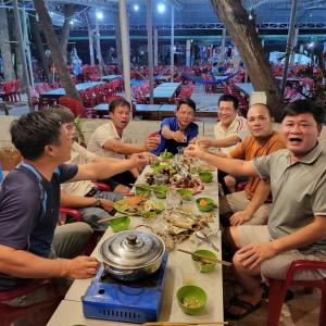 eine Gruppe von Menschen sitzt um einen Tisch herum und isst in der Unterkunft Vườn Dừa Cam Bình 1 in La Gi + 38 Fotos