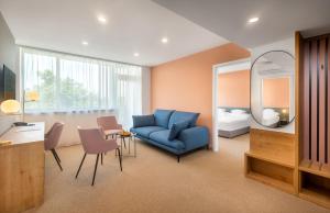 a living room with a blue couch and a bedroom at Hunguest Hotel Béke in Hajdúszoboszló
