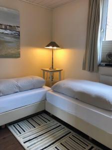 two beds in a room with a lamp on a table at Maris Ferienwohnung Nr 46 EG mit Terrasse in Scharbeutz +14 photos