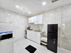 a kitchen with white cabinets and a black refrigerator at Amethyst Hoandedhdhoo in Kaadedhdhoo Airport +4 photos