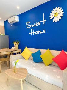 头顿The Sóng Vũng Tàu - Mochi House的蓝色墙壁前摆放着彩色枕头的沙发