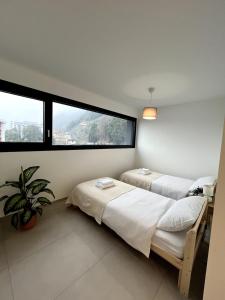 two beds in a room with a large window at Locarno Center - Casa Incanto - Free Parking & Washer in Locarno