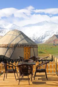 a deck with chairs and a gazebo with snow covered mountains at Yurt Glamping Edelweiss Meadow at the foot of Lenin Peak in Sary-Mogul