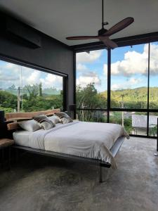 a bedroom with a large bed and large windows at Sky Lofts Airport Phuket in Ban Sakhu