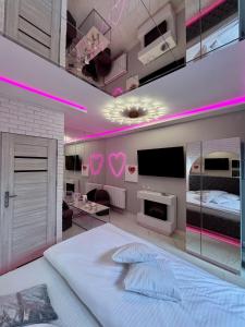 a bedroom with a white bed and pink lighting at Apartament "Love Island" Jacuzzi SPA z dużą wanną z hydromasażem dla Dwojga in Gniezno +13 photos