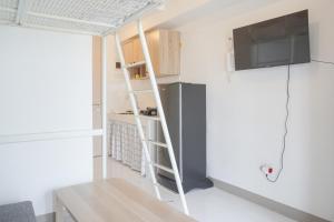 a small apartment with a ladder and a refrigerator at Simply Look and Homey Studio Tokyo Riverside PIK 2 Apartment By Travelio in Rawalembang