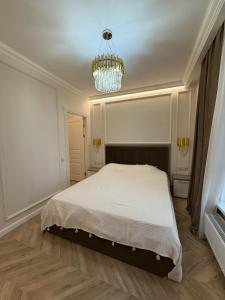 a bedroom with a white bed and a chandelier at Elite Residence Exclusive View in Chişinău