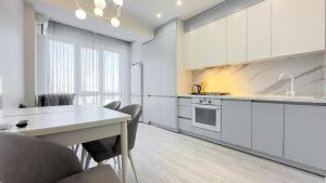 a kitchen with white cabinets and a table and chairs at Luxury Apartments Ismail Street in Chişinău