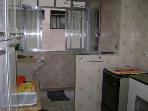a small kitchen with a sink and a stove at Apartamento Temporada Enseada in Guarujá